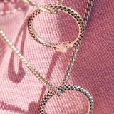 Silver necklaces with snake-shaped pendants on a pink fabric background
