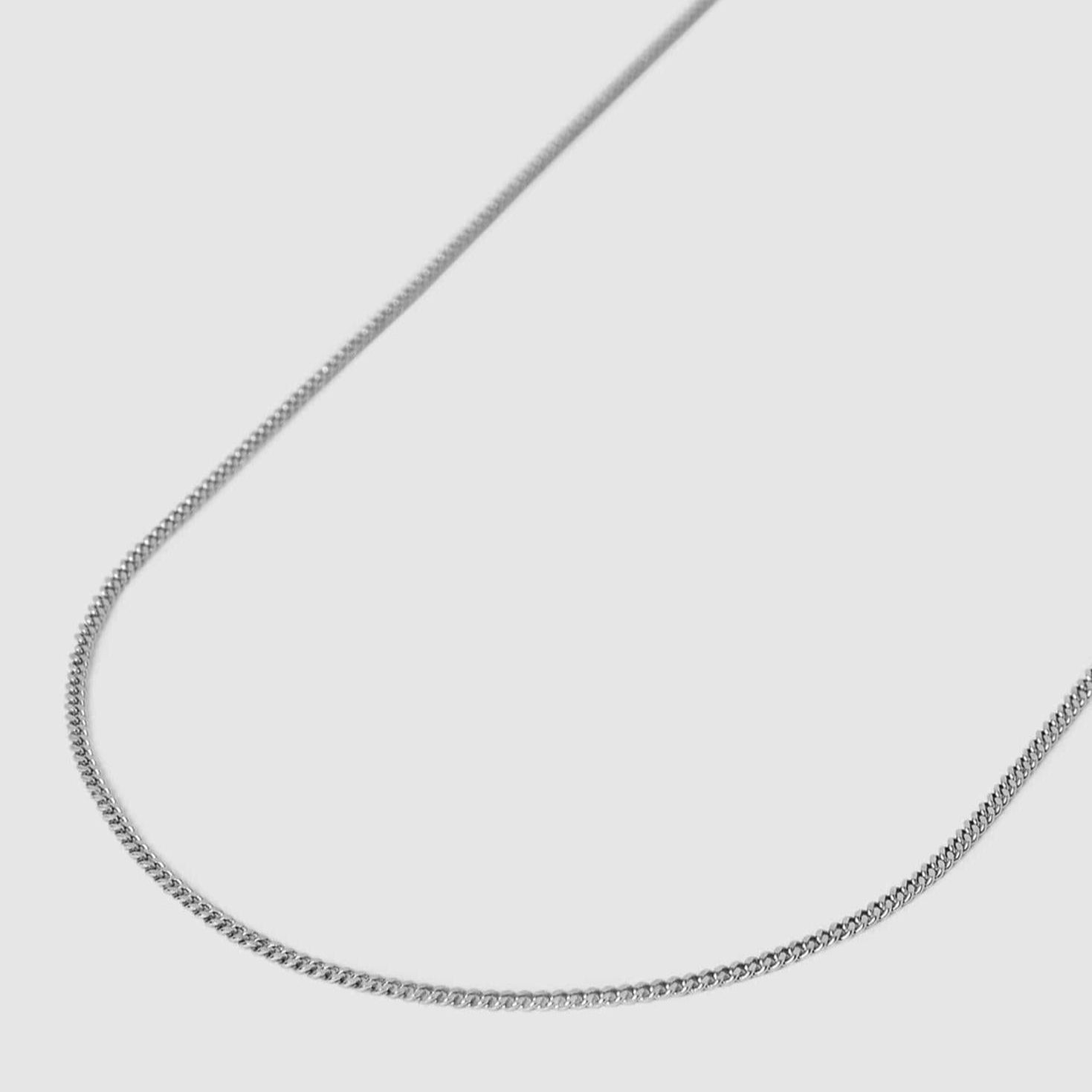 A thin silver chain necklace displayed against a plain light gray background.