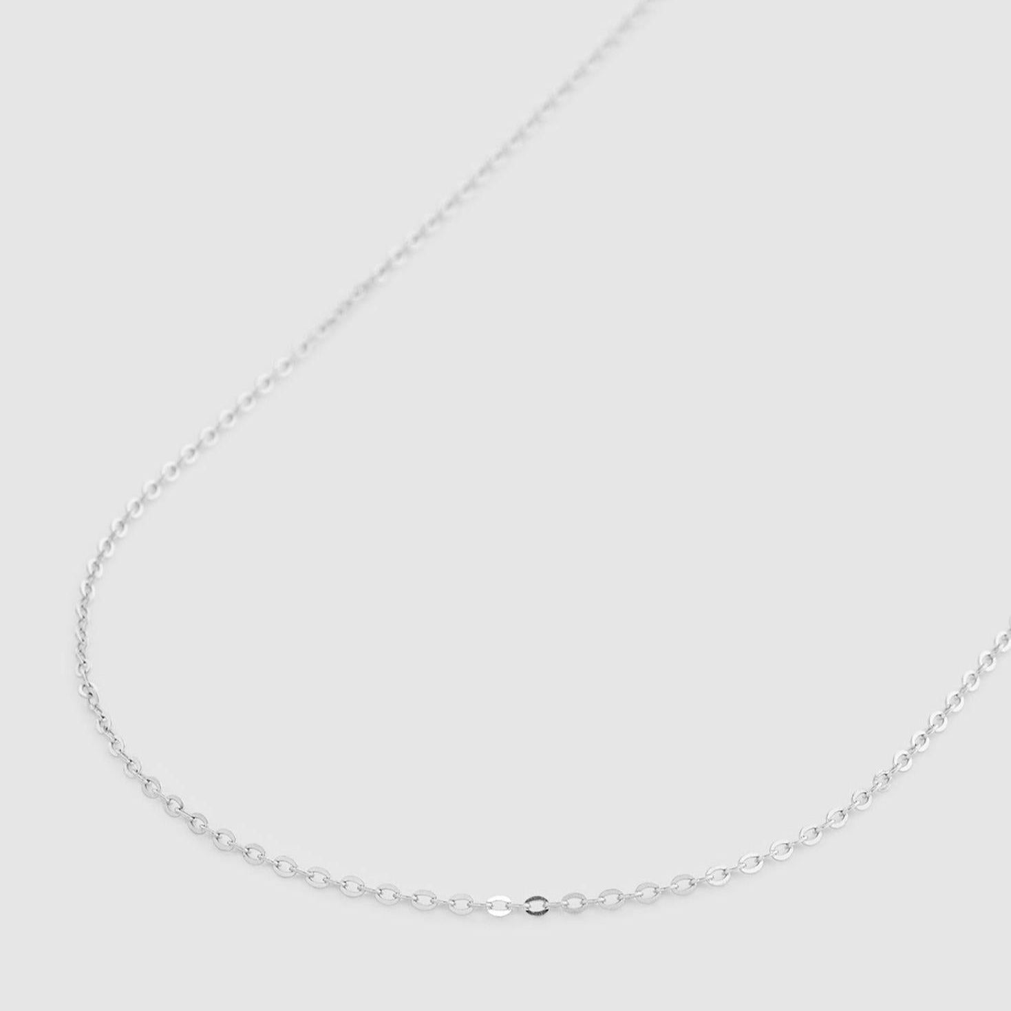 A delicate silver chain necklace displayed on a plain light gray background.